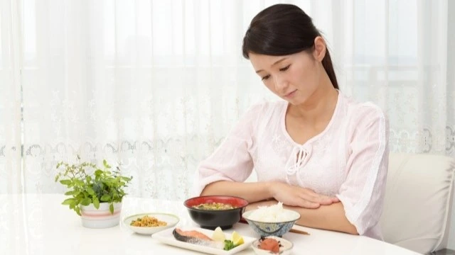 内臓の冷えにより食欲が出ない女性の写真