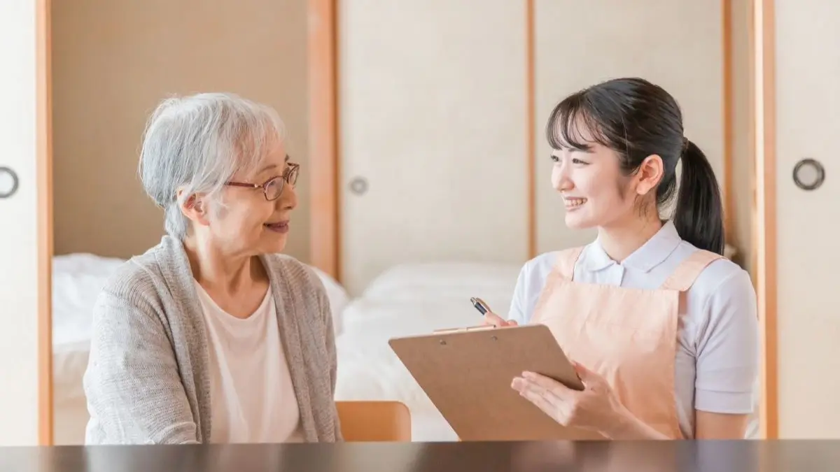 笑顔の鍼灸師と訪問マッサージを受ける高齢者